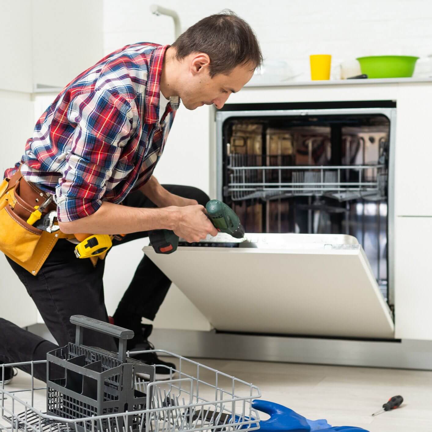 Person fixing dishwasher in kitchen