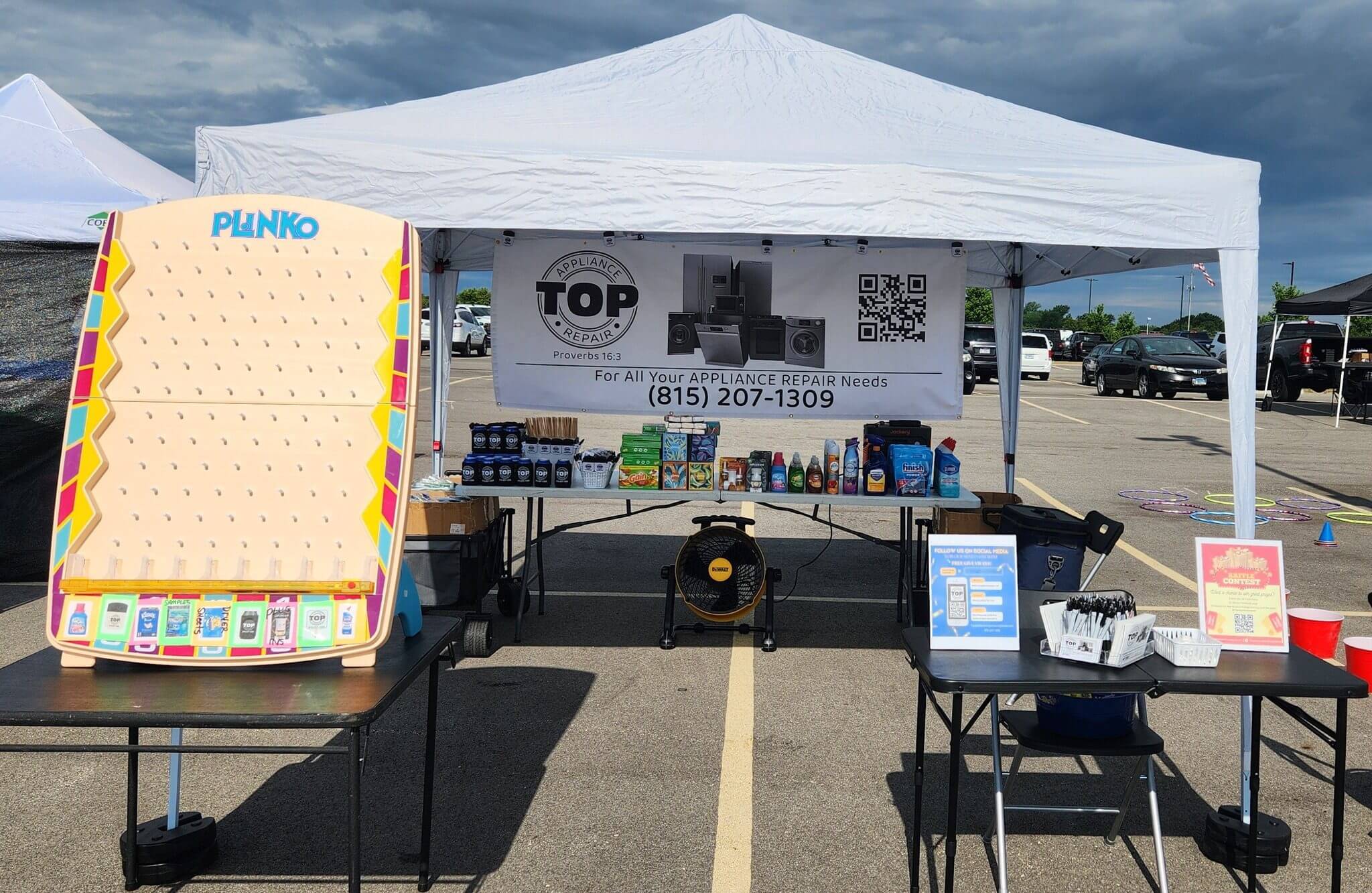 A booth tent set up in a parking lot with promotional materials and a chair.