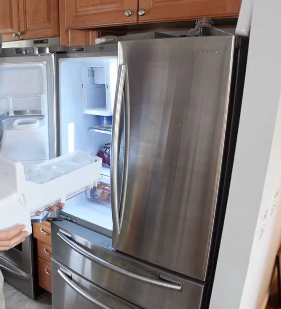 Open stainless steel refrigerator showing empty freezer drawer.