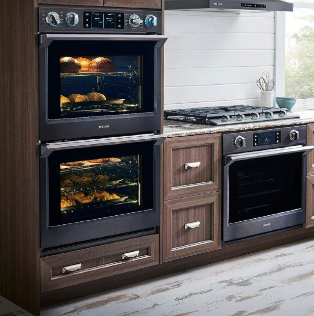 Modern kitchen with built-in double ovens and a stove, baking food inside.