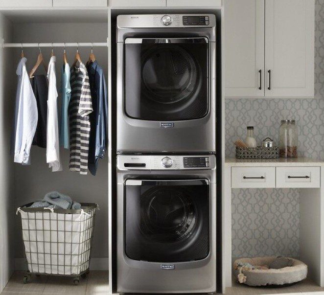 Modern laundry room with stacked washer and dryer, organized closet and laundry basket.